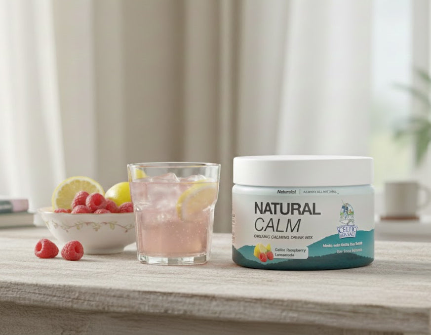 Jar of 'Natural Calm' supplement on a table with a glass of pink lemonade and fruit.